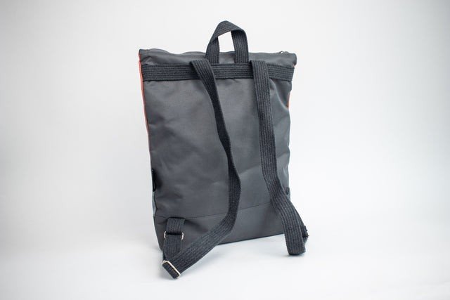 2. Back view of Muni salmon faux leather backpack showing adjustable straps and grey fabric