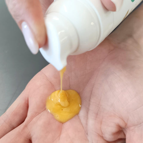 2. Close-up of HOIA homespa Firming Cellulite Cream Supermodel 2.0 being dispensed into hand, showing cream texture