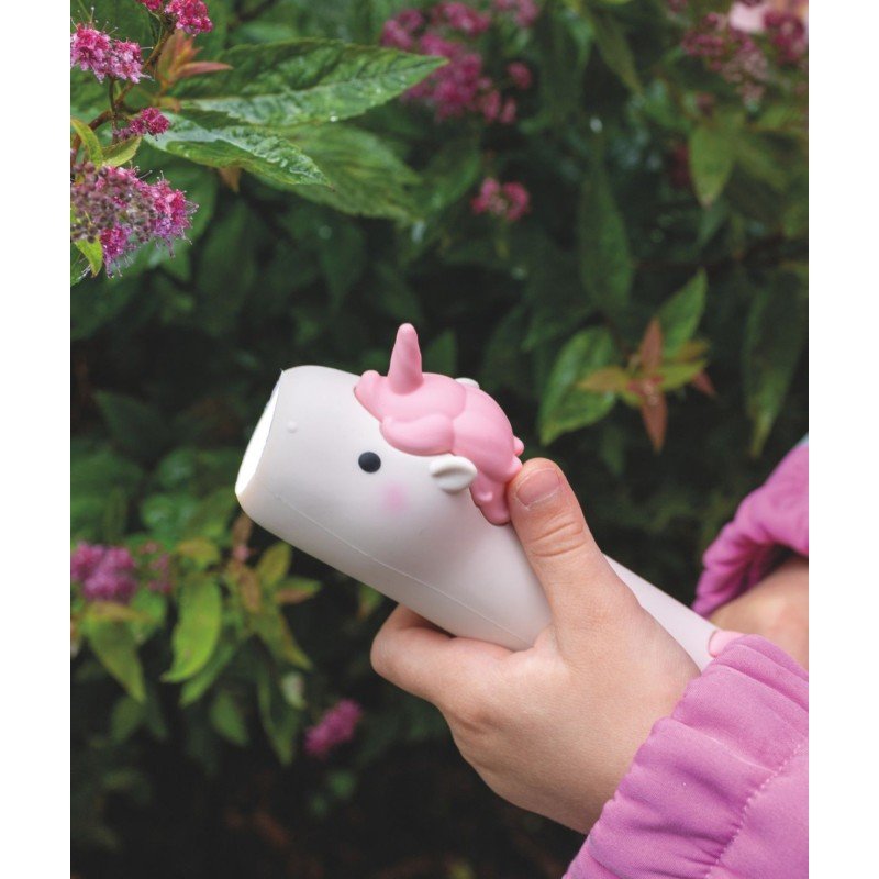 1. Child holding pink unicorn-shaped flashlight near flowering bushes, wearing a pink jacket