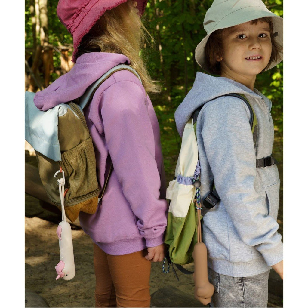 1. Two children with backpacks, one carrying a pink unicorn-shaped flashlight, standing in a wooded area