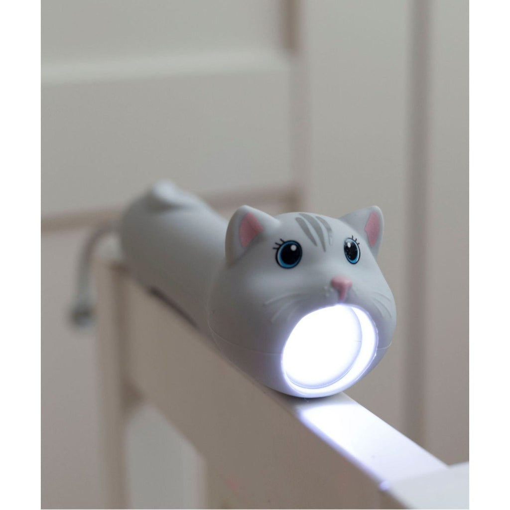 1. Cat-shaped flashlight resting on a railing, light on, in a dimly lit room