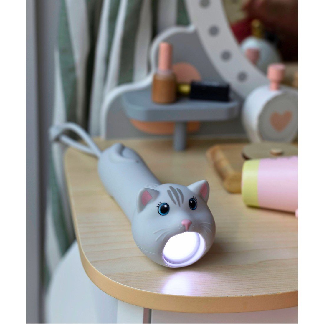 1. Cat-shaped flashlight on a child's vanity table, light on, surrounded by toys