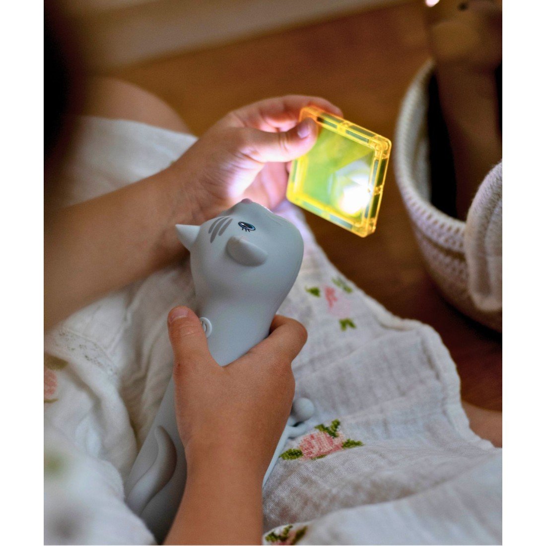 1. Child holding cat-shaped flashlight and yellow block, both illuminated