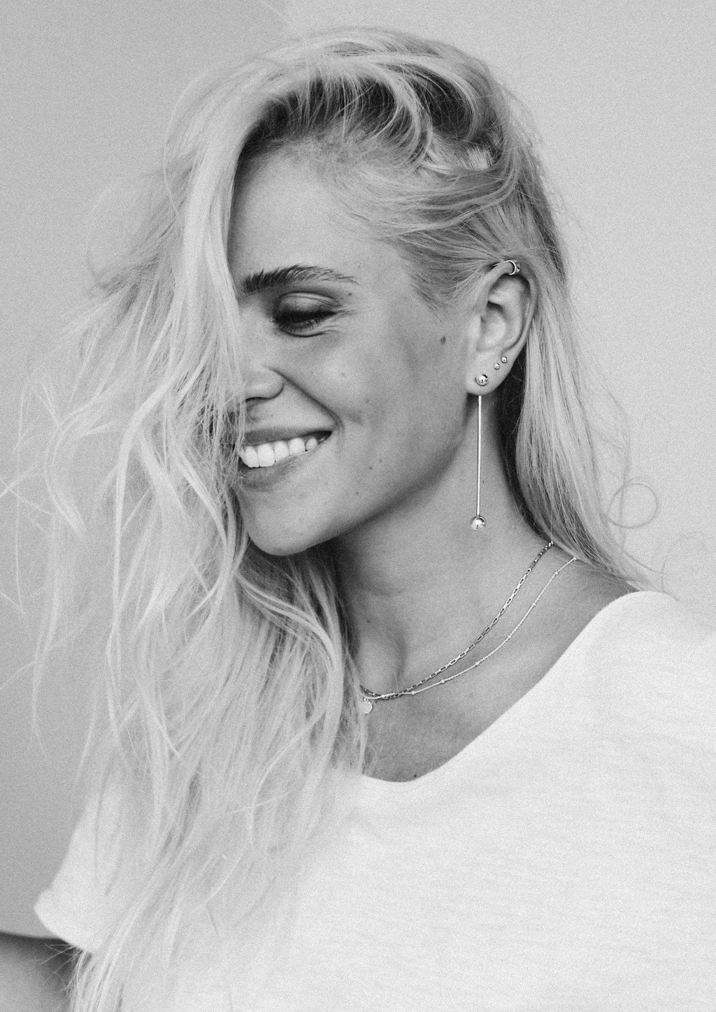 1. Woman wearing NO MORE Flat Upper Ear Cuff in silver, styled with long earrings and a necklace, in a lifestyle setting