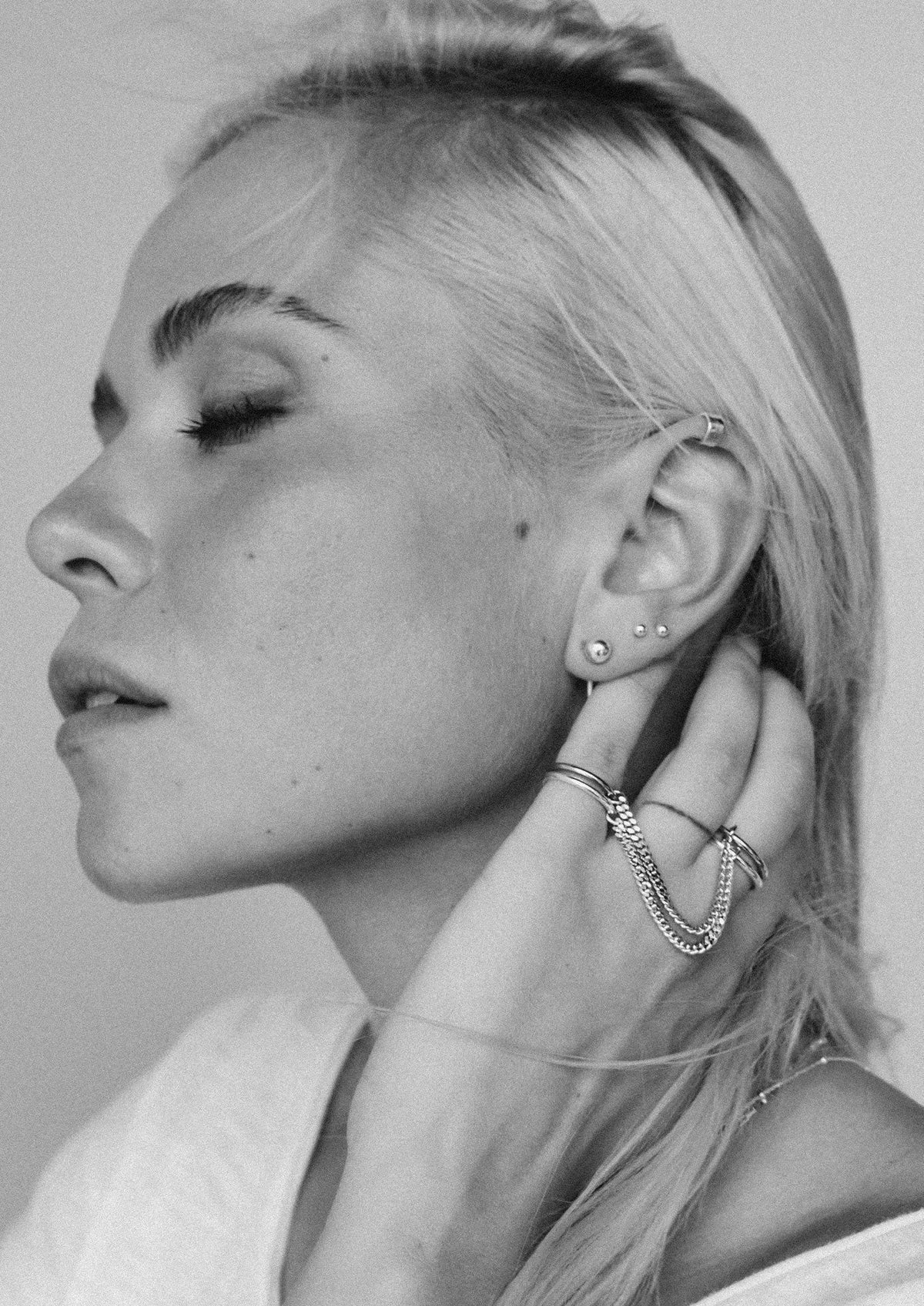 3. Close-up of woman wearing NO MORE Flat Upper Ear Cuff in silver, styled with multiple earrings and rings, in a lifestyle setting