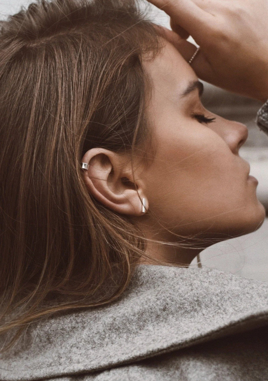 7. Close-up of woman wearing NO MORE Flat Upper Ear Cuff in silver, paired with hoop earrings, in a lifestyle setting