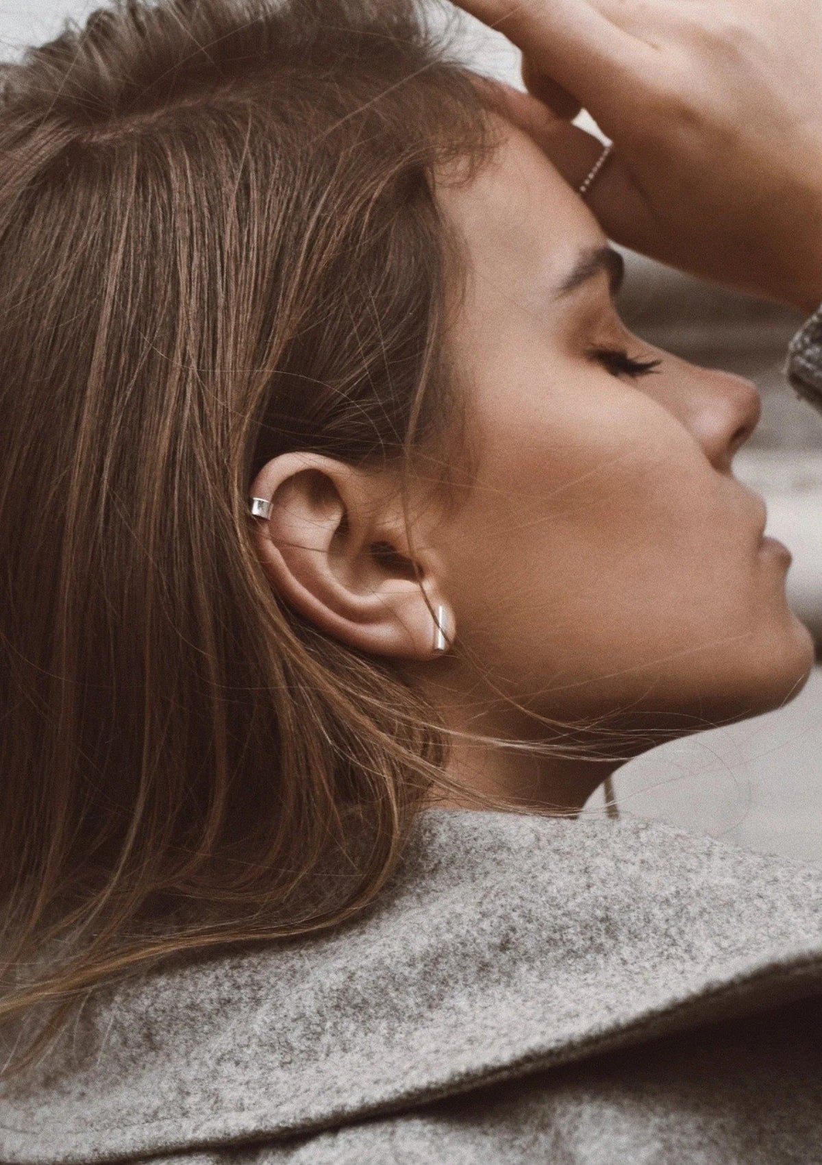7. Close-up of woman wearing NO MORE Flat Upper Ear Cuff in silver, paired with hoop earrings, in a lifestyle setting