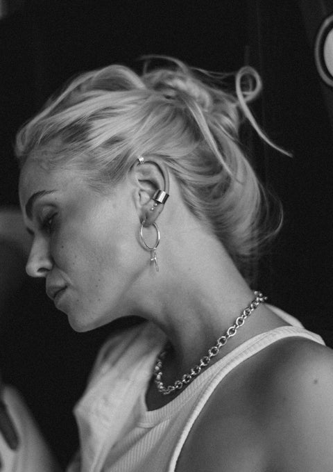 2. Woman with NO MORE Flat Upper Ear Cuff in silver, paired with chunky earrings and a necklace, in a lifestyle setting