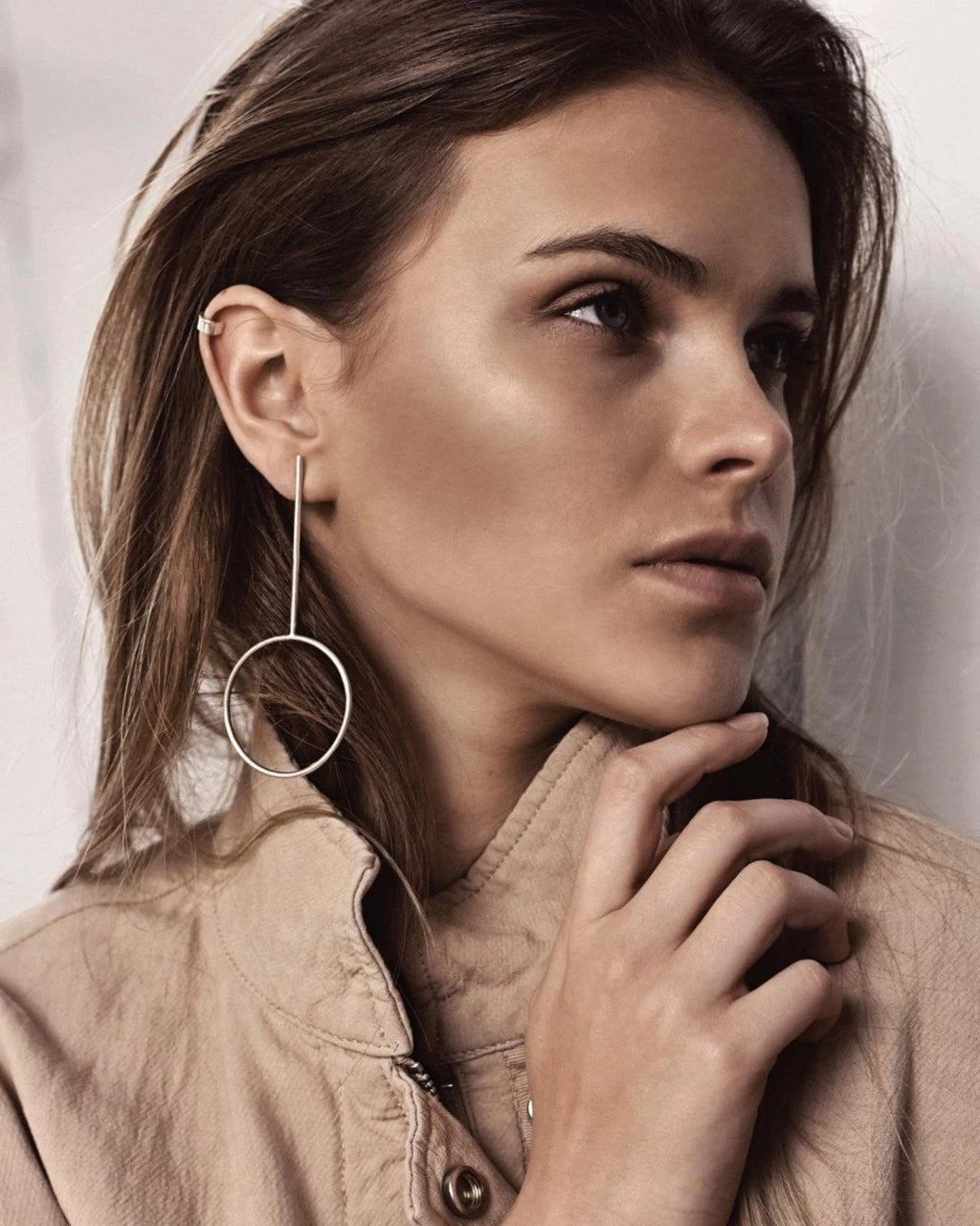 6. Woman wearing NO MORE Flat Upper Ear Cuff in silver, styled with long geometric earrings, in a studio setting