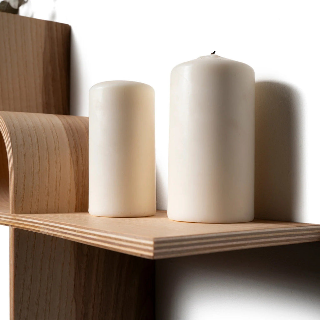 6. Close-up of two white candles on wooden floating shelf, highlighting smooth finish