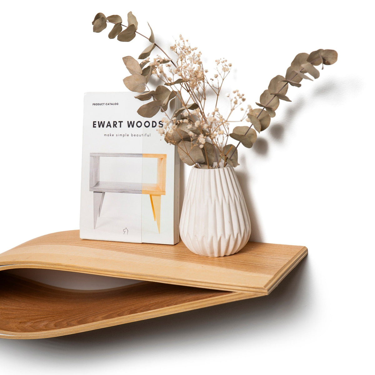 8. Ashwood floating wall shelf with decorative vase and Ewart Woods catalog on a white background