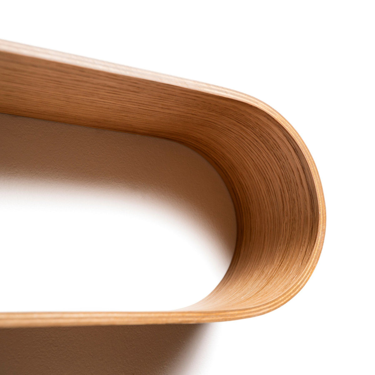 3. Close-up of curved edge of oval wooden wall shelf highlighting craftsmanship