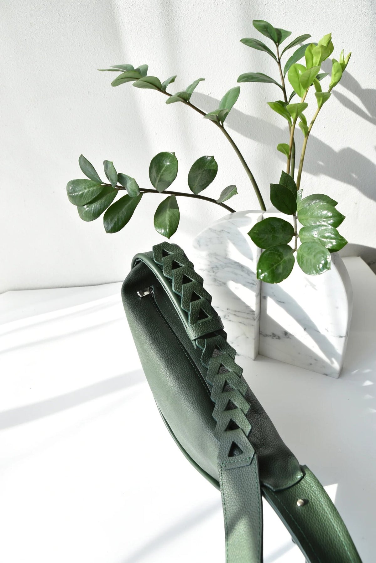 9. Dark green Flora Leather Bag by Gerda Retter Design, styled with plants in studio setting