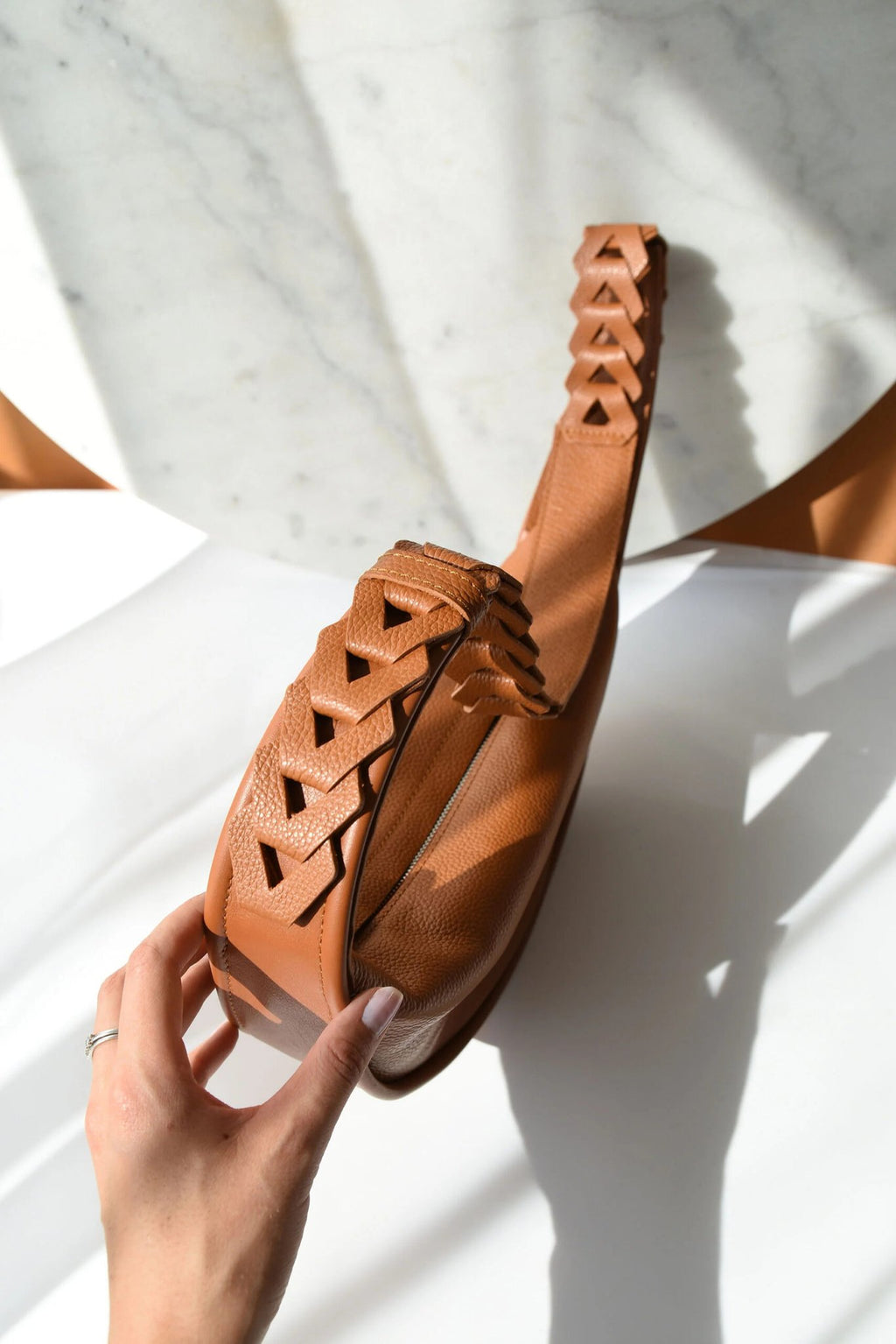 5. Caramel brown Flora Leather Bag by Gerda Retter Design, shown with braided strap and hand detail