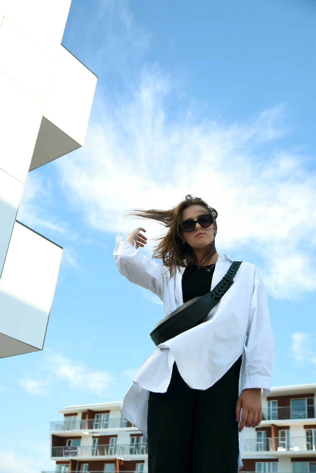 7. Woman wearing black Flora Leather Bag by Gerda Retter Design, styled with white shirt in urban setting