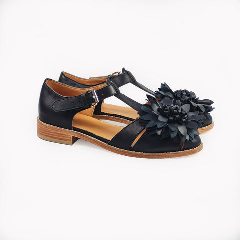 3. Side view of women's black leather fisherman sandals with flower detail and silver buckle