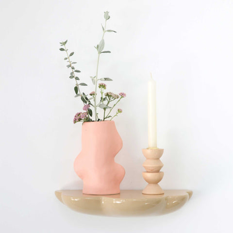 1. Fluxo Ceramic Vase in pink displayed on a shelf with flowers and a candle, showcasing its unique flowing design
