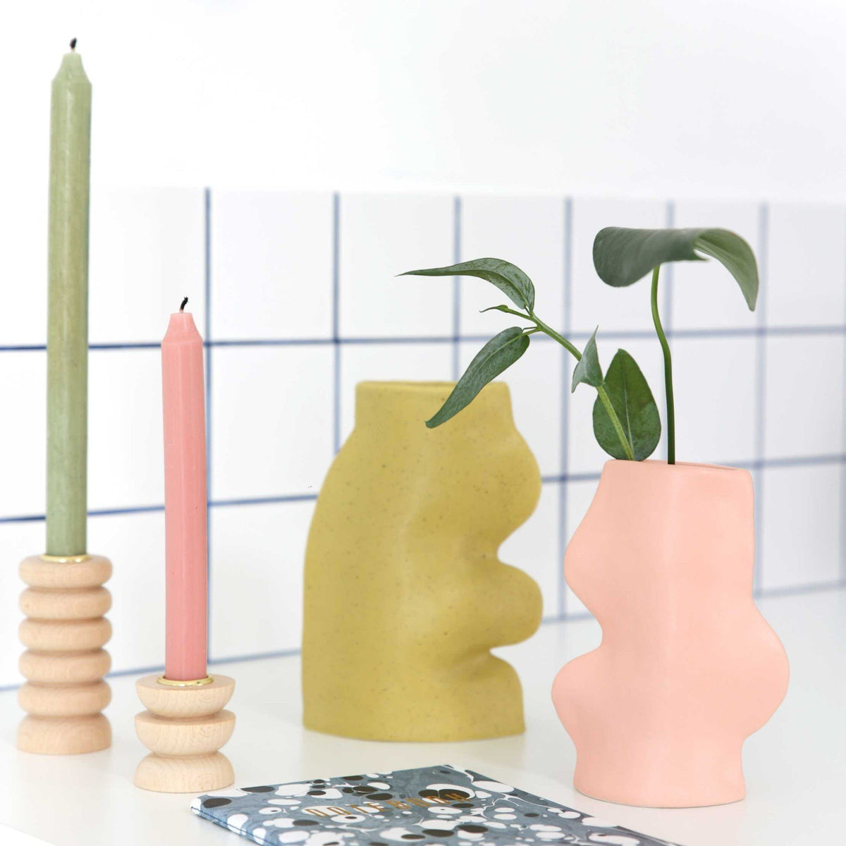 4. Fluxo Ceramic Vase in pink with greenery, paired with candles, illustrating its artisanal charm in a modern setting