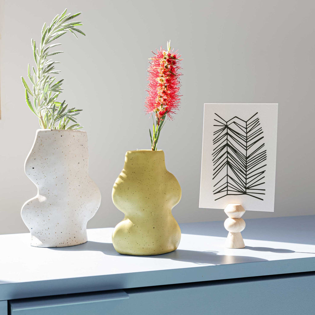 3. Fluxo Ceramic Vases in white and yellow on a table, styled with plants and artwork