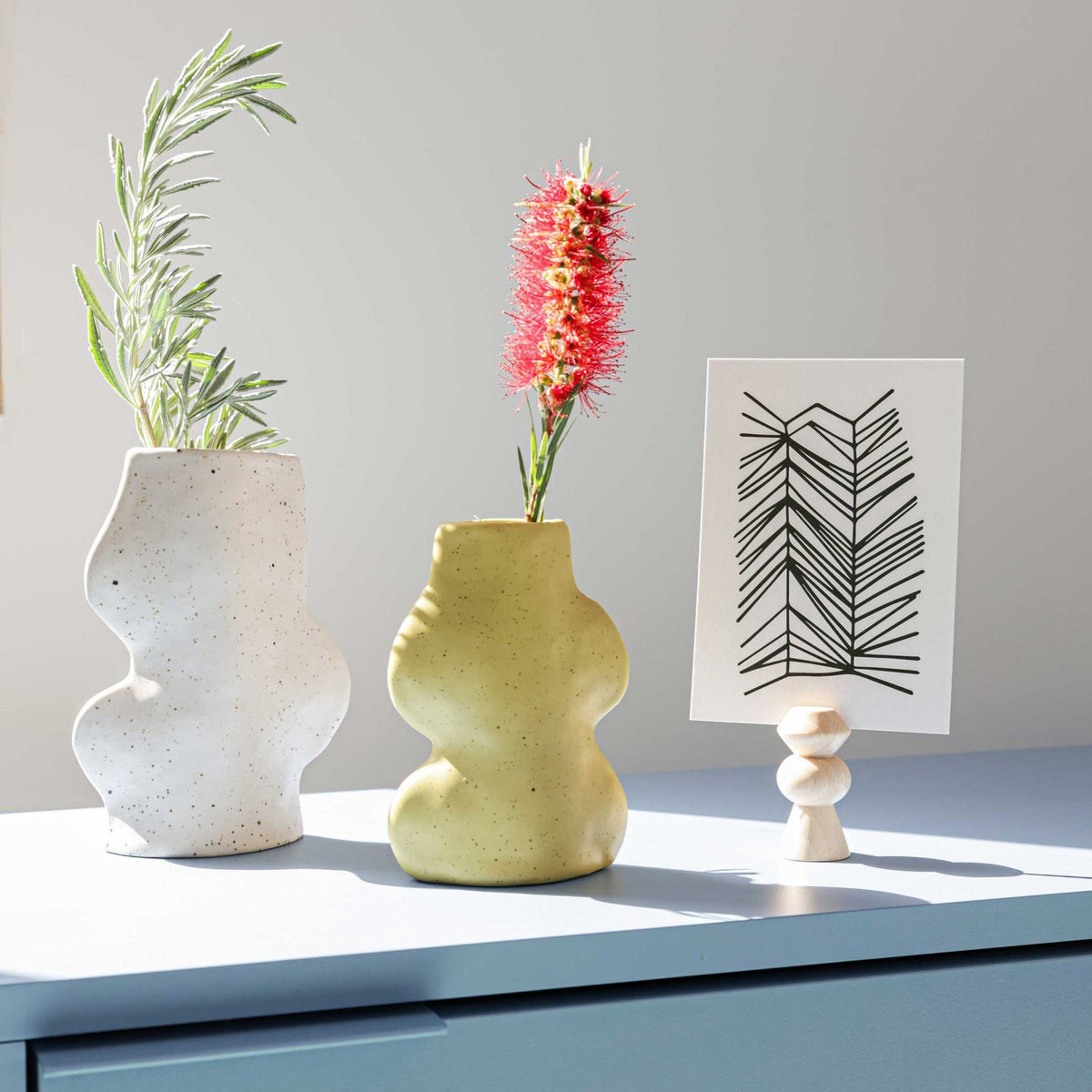 3. Fluxo Ceramic Vases in white and yellow on a table, styled with plants and artwork