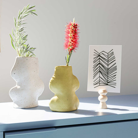 3. Fluxo Ceramic Vases in white and yellow on a table, styled with plants and artwork