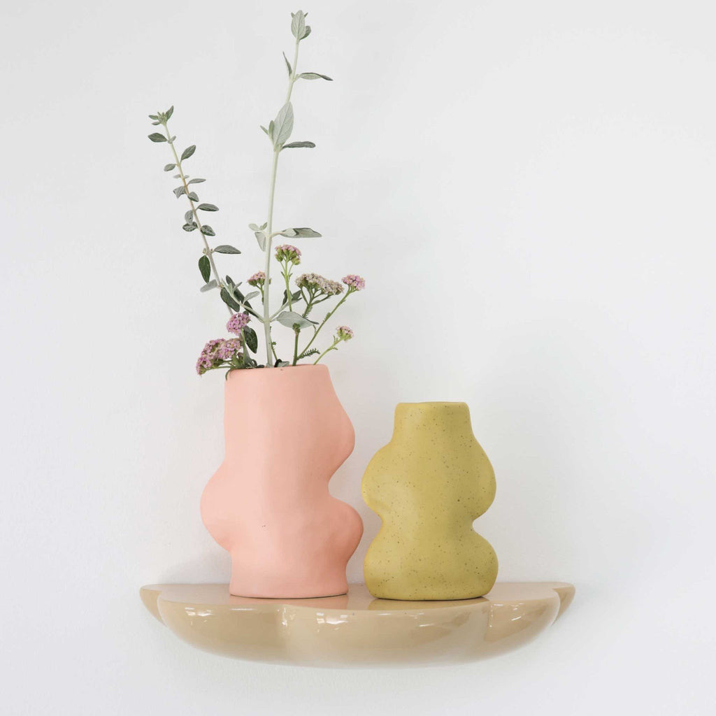 1. Lifestyle image of Fluxo Ceramic Vase in pistachio and pink, styled with flowers on a shelf