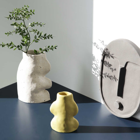 3. Lifestyle image of Fluxo Ceramic Vase in pistachio with a plant, next to a white vase and wall art