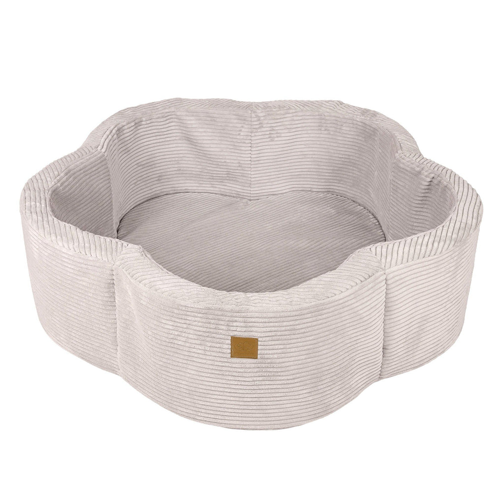 4. Ecru flower-shaped foam baby ball pit with ribbed texture and brown brand patch, shown empty in studio setting