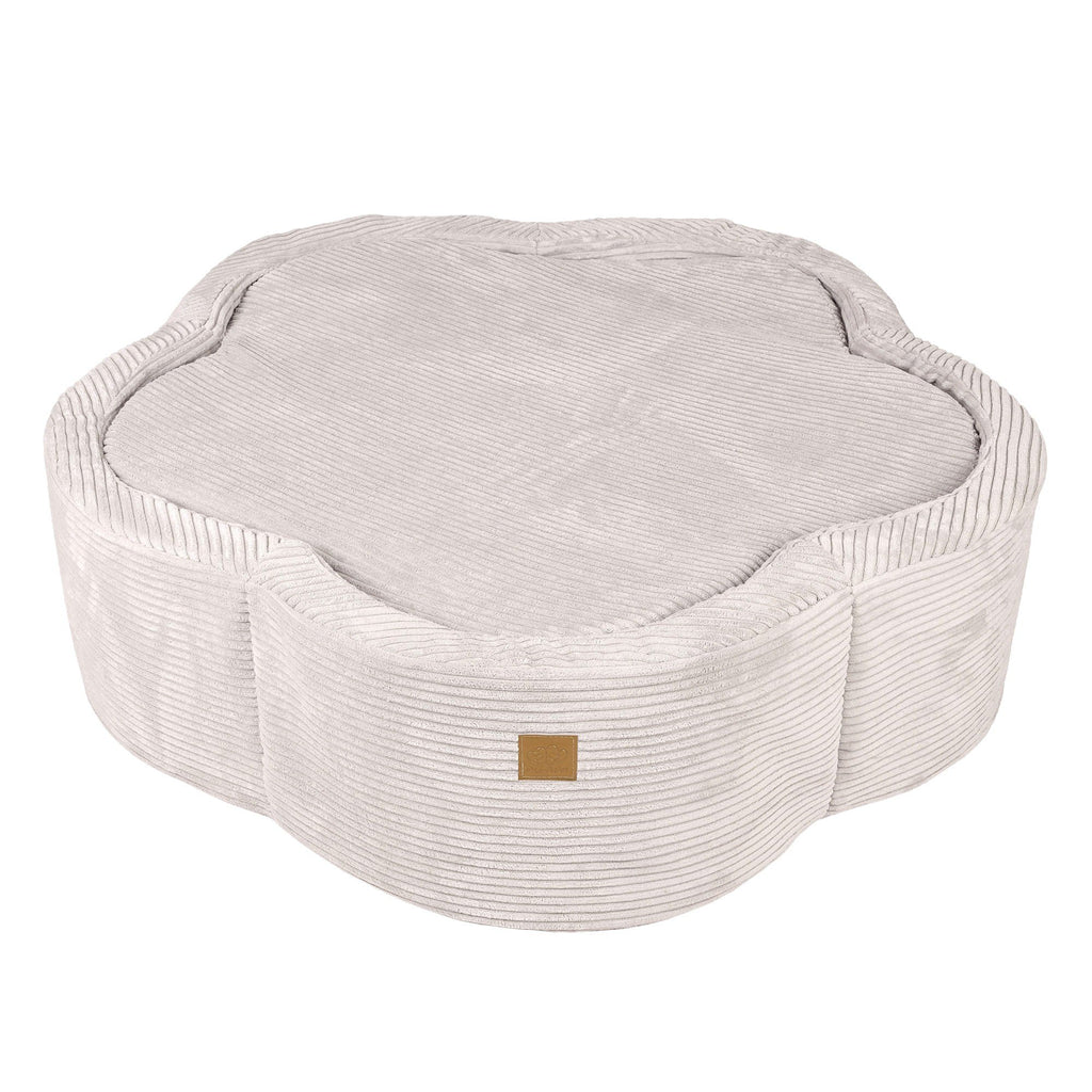 2. Ecru flower-shaped foam baby ball pit with ribbed texture and brown brand patch, shown with cover on in studio setting