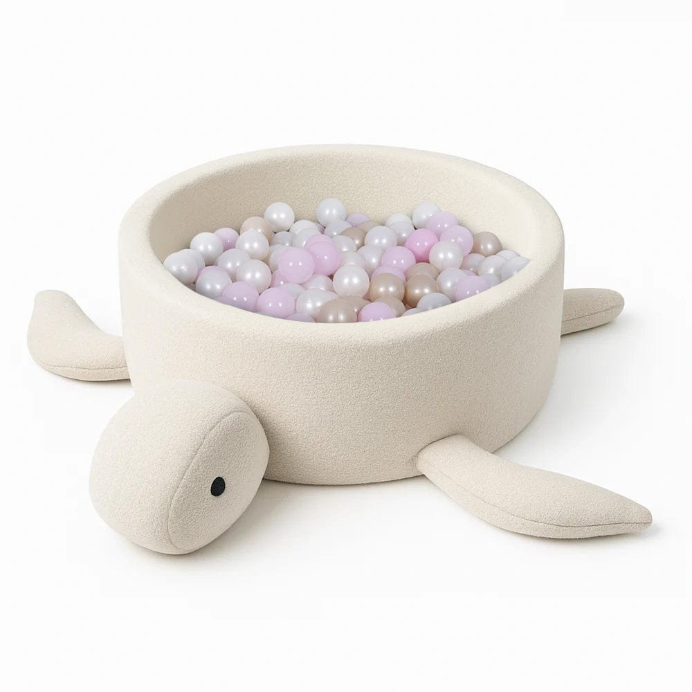 2. Turtle-shaped baby ball pit in cream beige boucle fabric filled with pastel balls, shown in studio setting