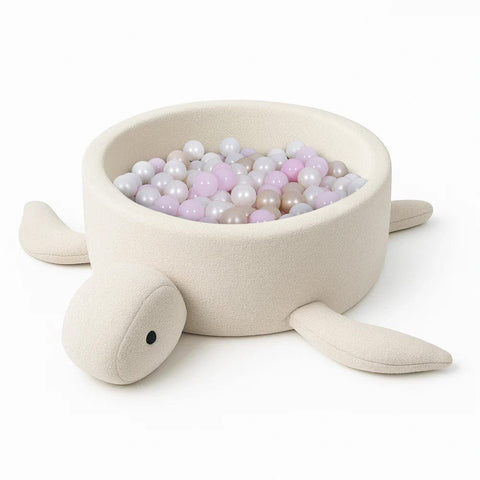 2. Turtle-shaped baby ball pit in cream beige boucle fabric filled with pastel balls, shown in studio setting