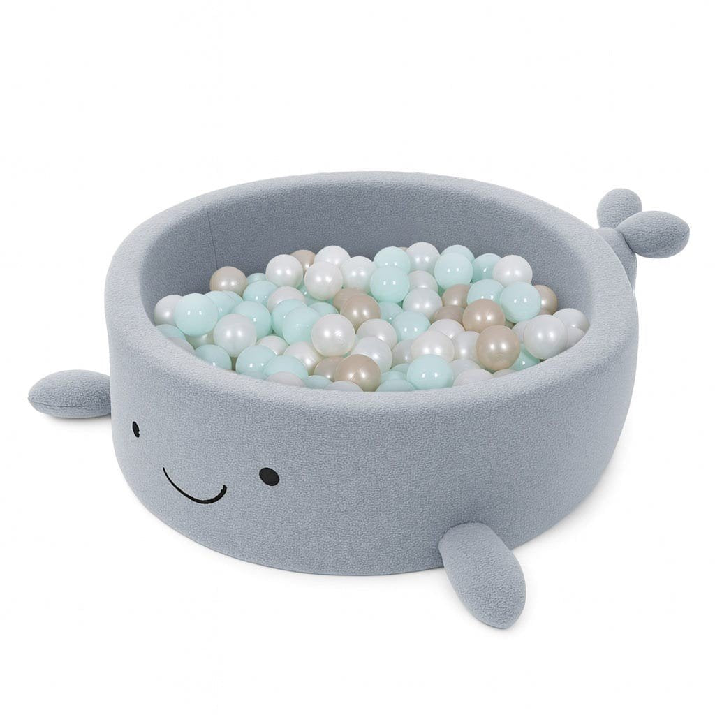 2. Whale-shaped baby ball pit in dusty ice blue boucle fabric filled with pastel-colored balls, featuring soft fins and a smiling face