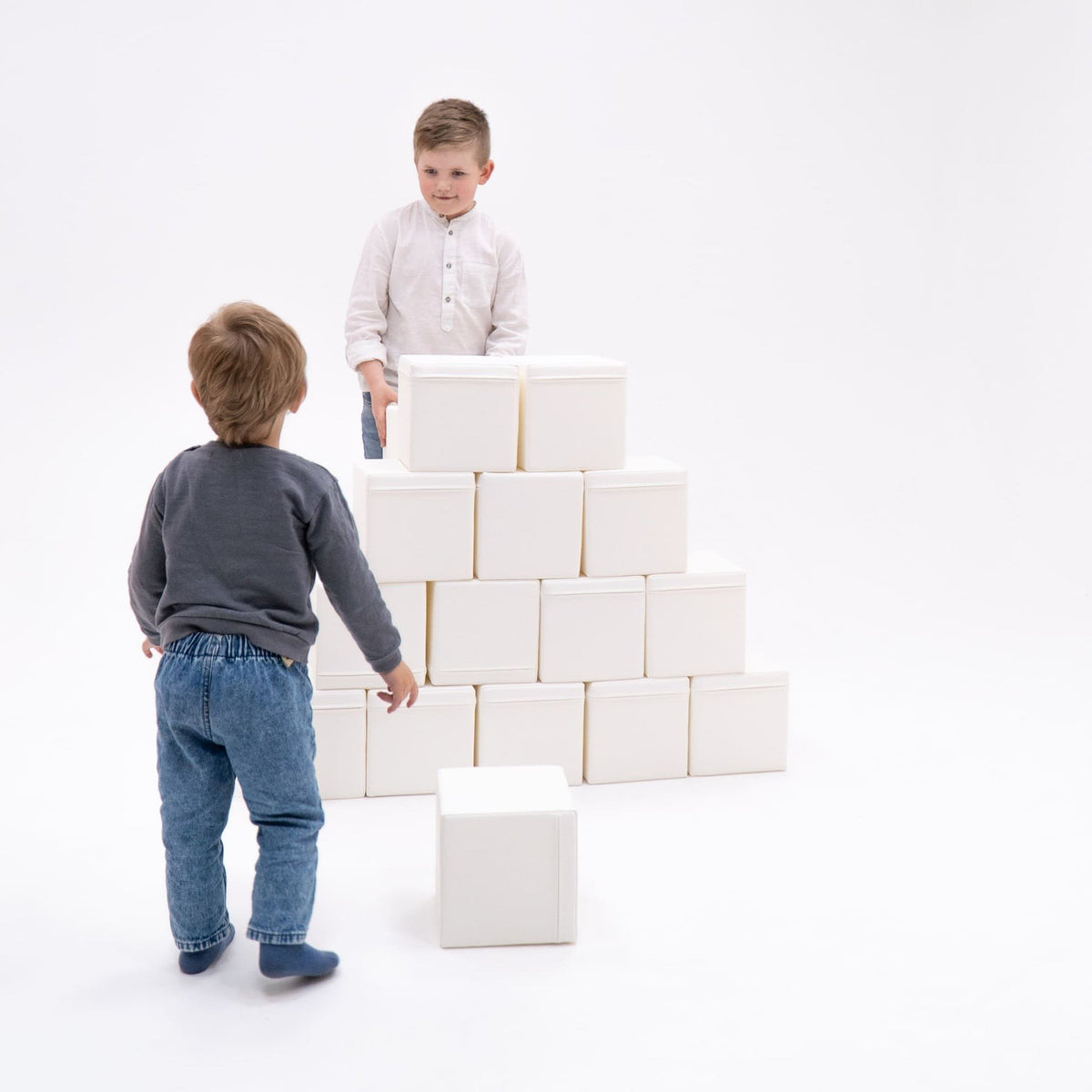 1. Two children playing with foam building blocks in a white studio setting