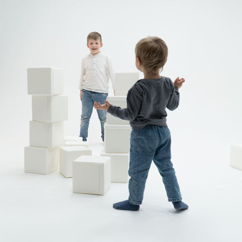 1. Two children playing with foam building blocks in a bright room, encouraging creativity and spatial play