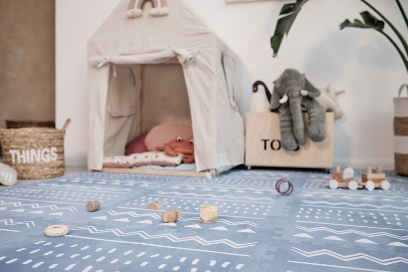 5. Blue OLYA KIDS Boho puzzle playmat in playroom with tent, toys, and storage baskets