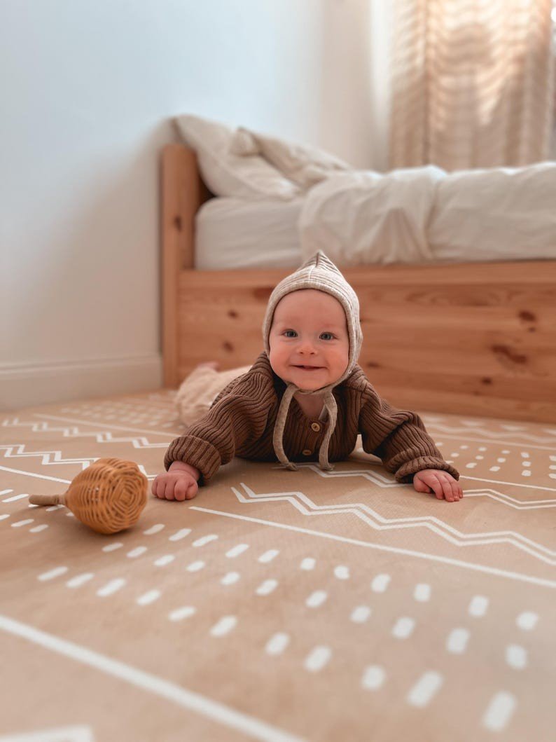 1. Baby lying on OLYA KIDS Boho sand puzzle playmat in a bright, minimalist bedroom