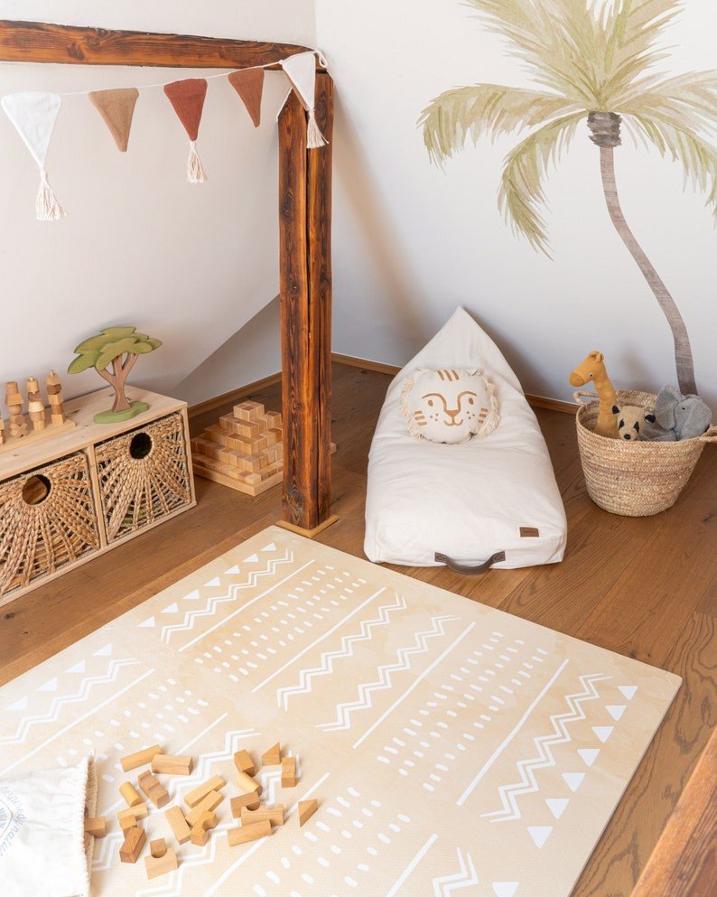 3. Playroom corner with OLYA KIDS Boho sand puzzle playmat, bean bag, and wooden toys under a decorative banner