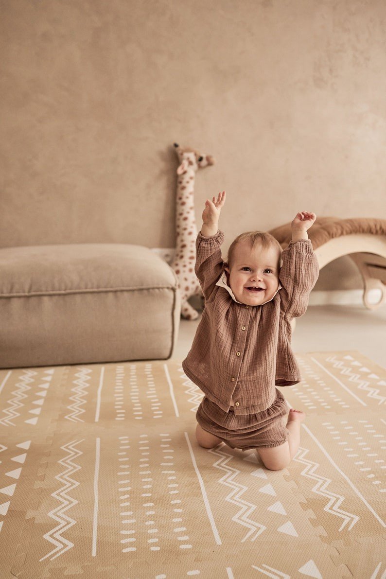 1. Smiling baby on OLYA KIDS Boho sand puzzle playmat in a cozy room with neutral decor
