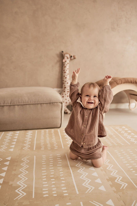 1. Smiling baby on OLYA KIDS Boho sand puzzle playmat in a cozy room with neutral decor