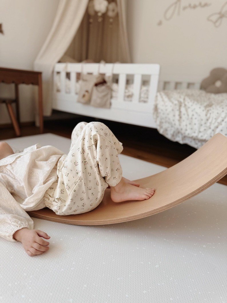 1. Child playing on wooden rocker over OLYA KIDS cashmere spots playmat in cozy nursery