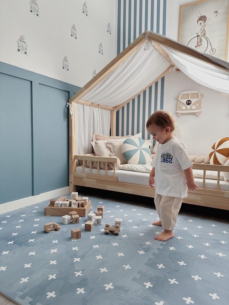 1. Toddler standing on OLYA KIDS Cross Azure foam puzzle playmat with wooden blocks in stylish nursery