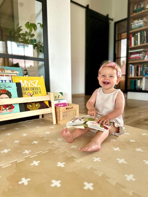 1. Smiling baby sitting on OLYA KIDS Cross sand foam puzzle playmat in a cozy room with bookshelves