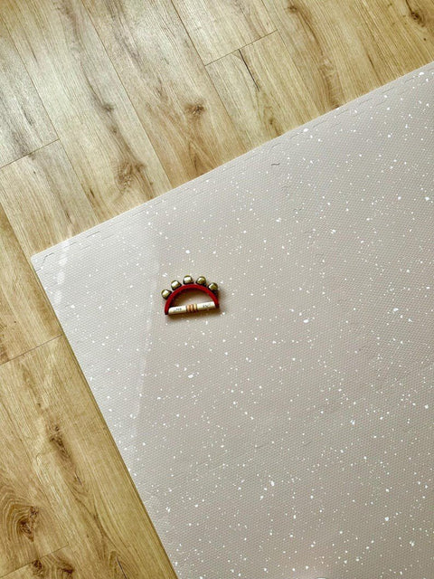 1. Cappuccino foam puzzle playmat with white spots on wooden floor, featuring a small red tambourine toy