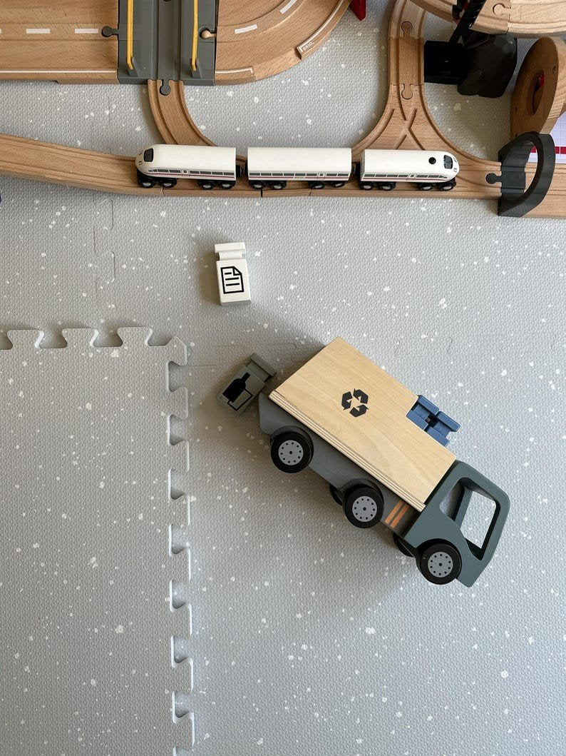 1. Foam puzzle playmat in dove color with toy train and recycling truck on top, showcasing play area setup