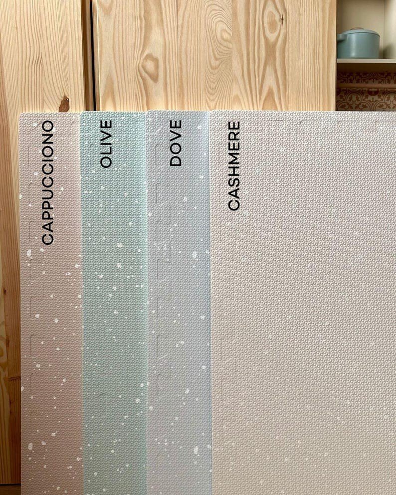 2. Studio shot of four foam puzzle playmats in cappuccino, olive, dove, and cashmere colors with labeled sections