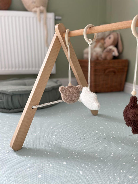 1. Baby play area with wooden toy gym on olive foam puzzle playmat in cozy room setting
