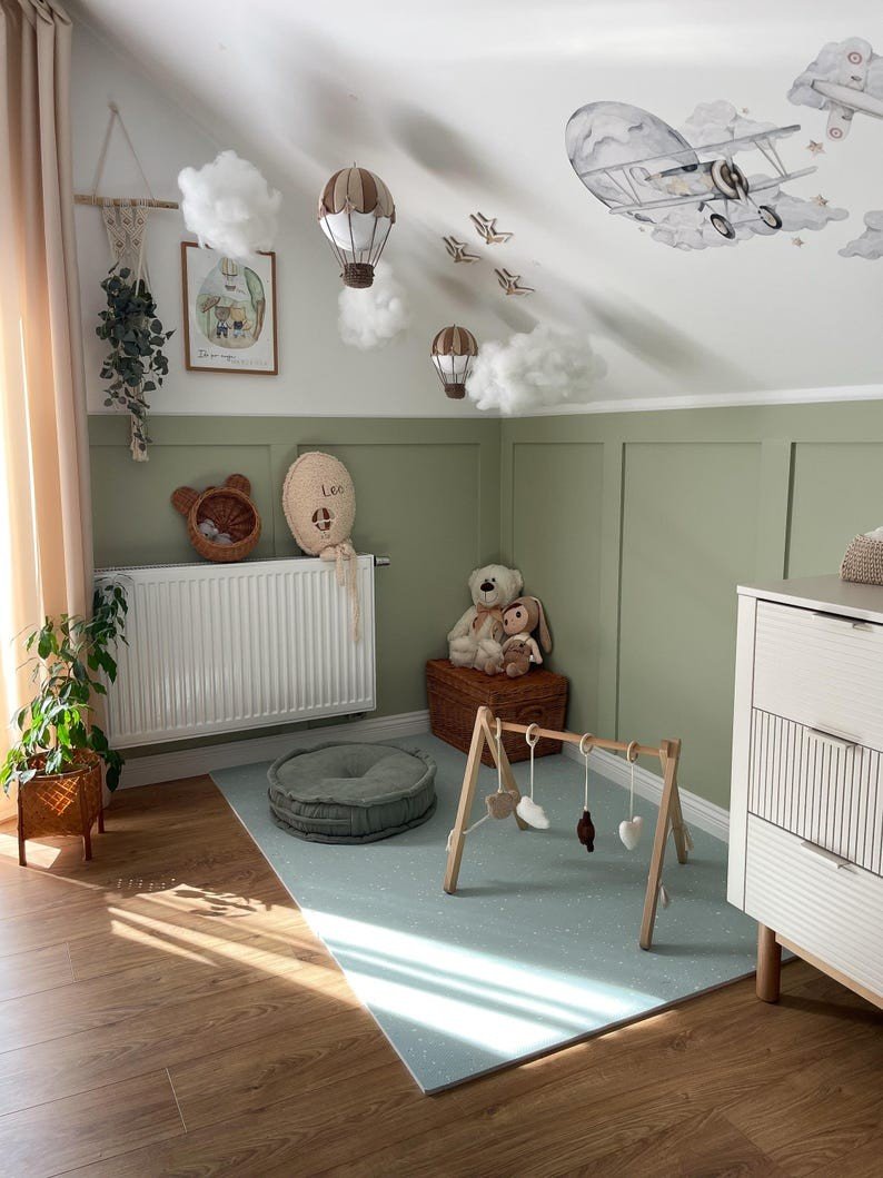 6. Nursery room with olive foam puzzle playmat, wooden toy gym, and decorative wall art