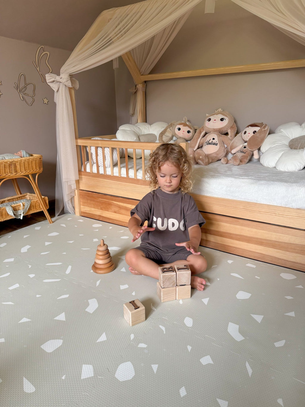 1. Child playing with wooden blocks on OLYA KIDS Terrazzo Dove foam puzzle playmat in cozy bedroom setting