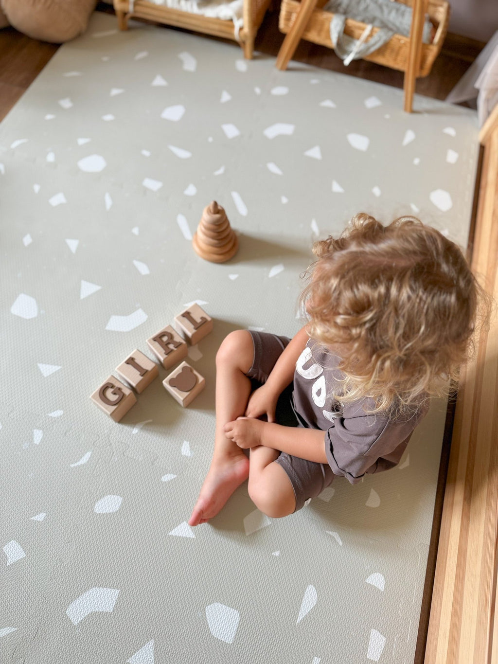 3. Child sitting on OLYA KIDS Terrazzo Dove foam puzzle playmat with wooden blocks and stacking toy
