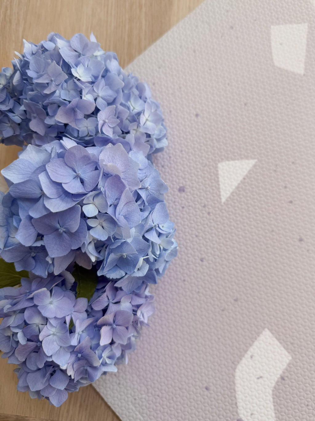 4. Close-up of lavender terrazzo playmat with blue hydrangeas on corner